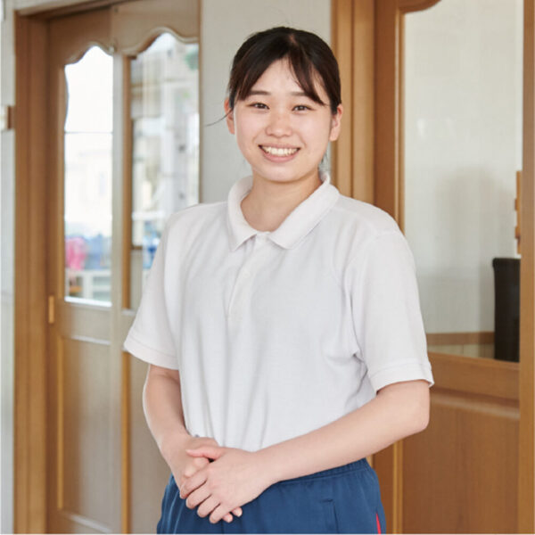 ちくみ幼稚園の園舎内で、笑顔で立つみさき先生
