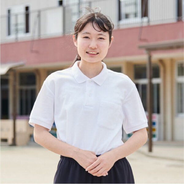 ちくみ幼稚園の園庭で、園舎を背に立つりりか先生