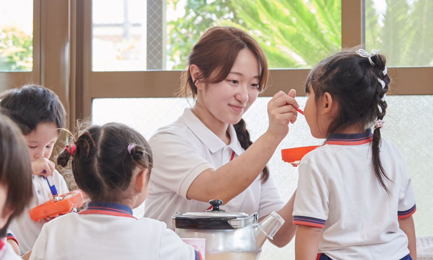 お弁当の時間に、子どもの口もとへスプーンを運んでお手伝いするもえ先生