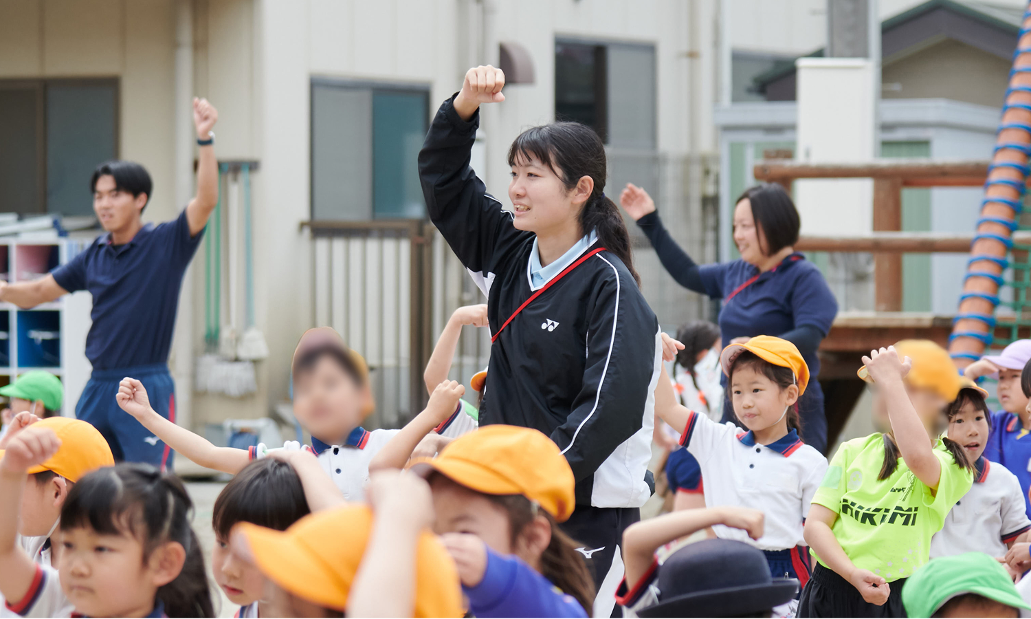 園庭で子どもたちと一緒にこぶしを上げ、体操をするりりか先生