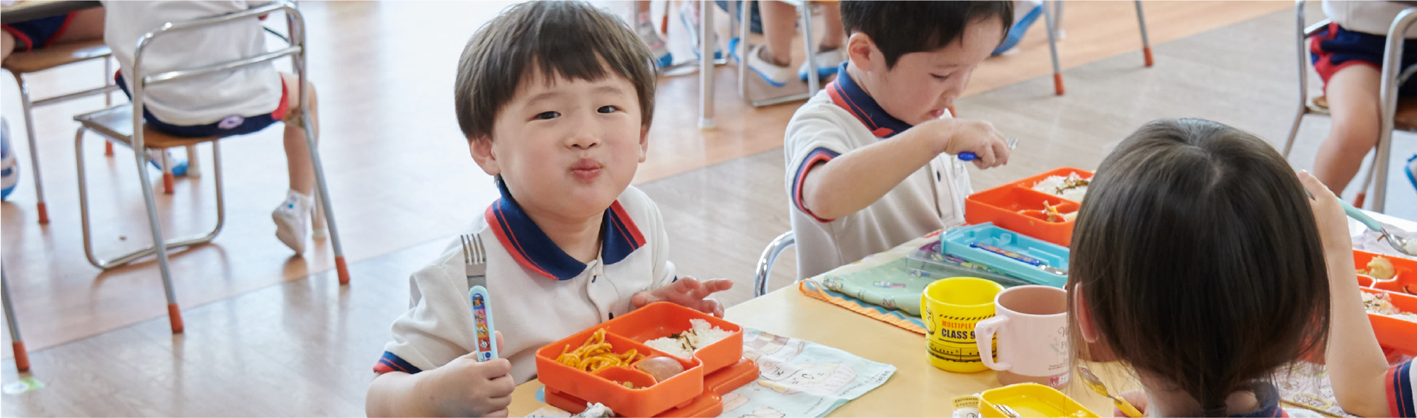お弁当の時間に、口いっぱいにほおばってこちらを見る男の子